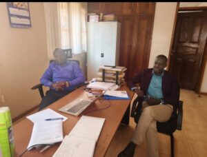 Kayunga District Registration Officer, Muhammed Mpiima (L) briefing Deputy RDC, Trevor Solomon Baleke at the District NIRA office, Tuesday
